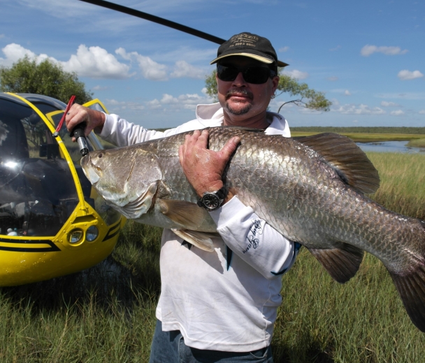 Person holding large fish next to helicopter